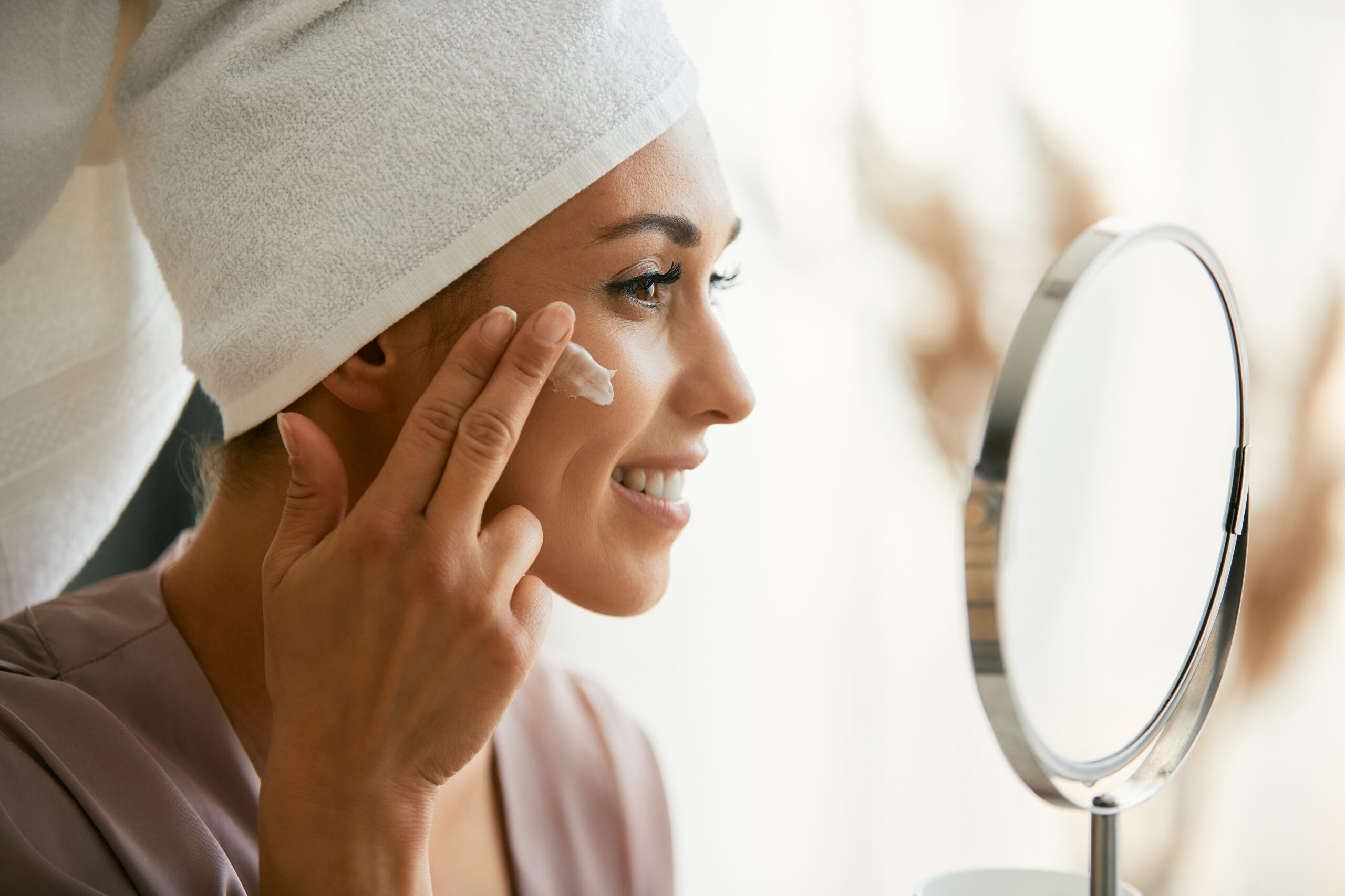 Woman applying a retinal night cream as part of a routine featuring a vitamin C serum in Australia and active skincare products to support collagen.