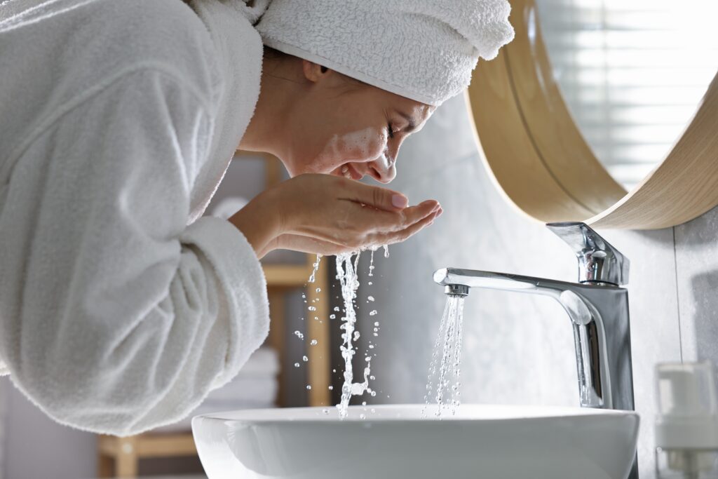 Woman washing her face with a sensitive skin cleanser as part of an active skincare routine using Australian skincare products.